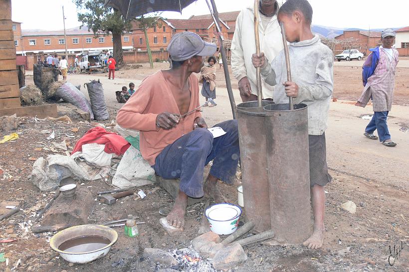 P1100247.JPG - Un forgeron. Son fils actionne les soufflets (alternativement deux pistons) tandis que lui bouche les trous de vieilles marmites avec un fer chauffé et de l'étain.