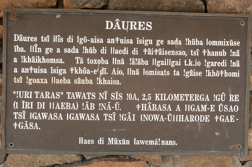 P1140038.JPG - C'est au coeur du Brandberg (après 1h30 de marche sous plus de 35°C) que l'on peut voir des peintures de l'époque préhistorique. Ici un panneau écrit en Damara Nama. Cette langue se parle en employant 4 types de "clic" faits avec la langue. (les symboles des clics sont "!",  "l", "ll" et le T avec une double barre)